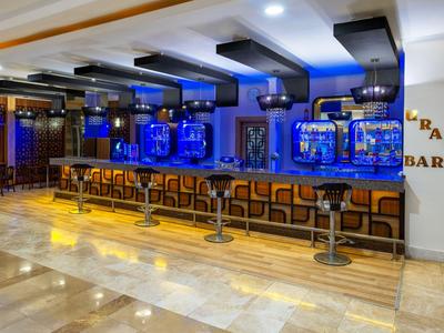 Bar d'hôtel moderne avec étagères éclairées en bleu et longs tabourets de bar.