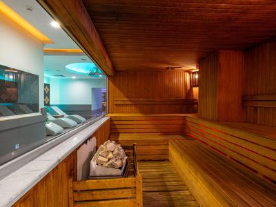 Vue intérieure d'un sauna en bois à côté d'une piscine avec des transats.