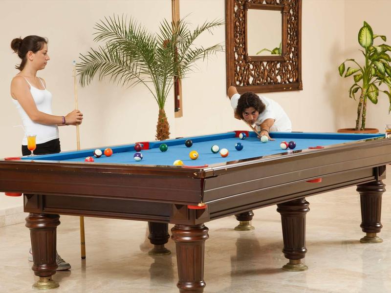 Zwei Frauen spielen Billard an einem großen Holztisch in einem hellen, gemütlichen Raum.