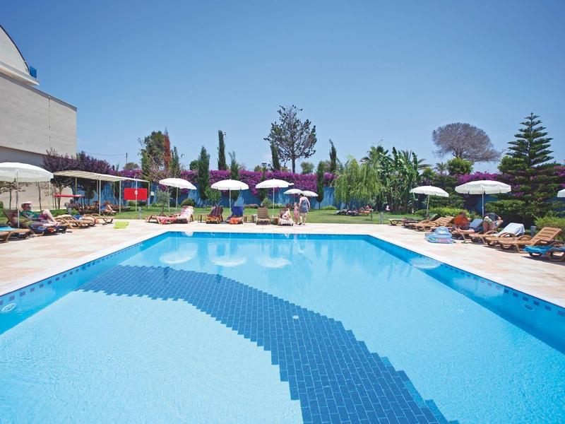 Großes rechteckiges Schwimmbecken mit blauen Wasser, umgeben von Liegestühlen und Sonnenschirmen.