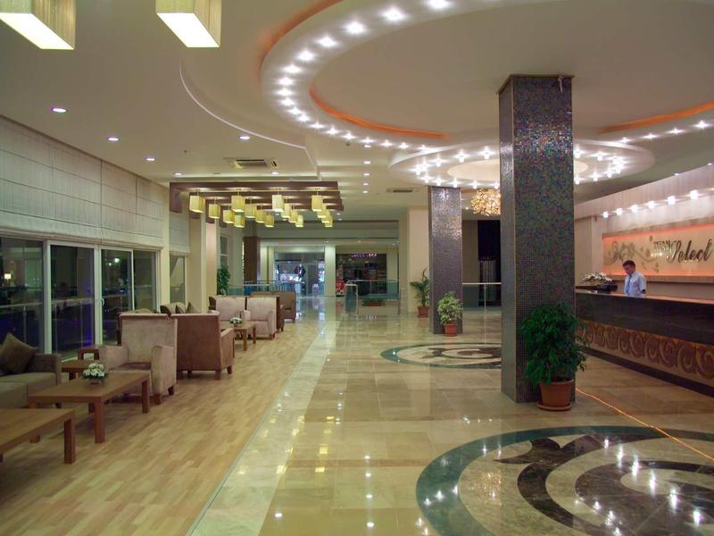 Große, helle Hotellobby mit Marmorfußboden, Sitzgruppen, Deckenleuchten und Empfangstresen.