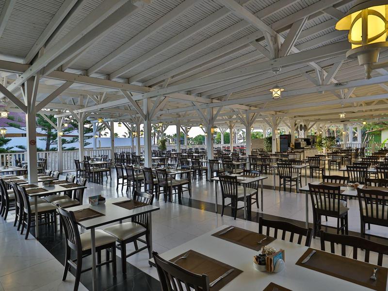 Velká krytá venkovní restaurace s mnoha stoly a židlemi.