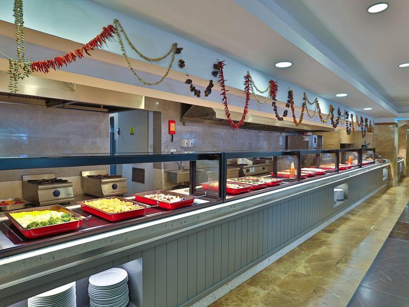 Dlouhá moderní bufetová část s teplými jídly v ohřívaných nádobách a dekorativními girlandami.