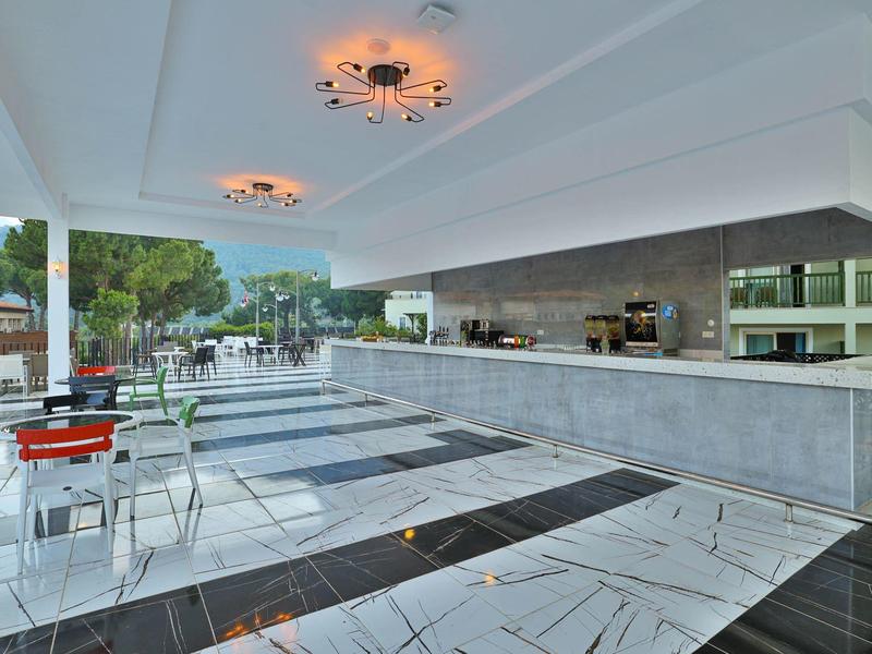 Moderní venkovní část hotelu se sezením a dlouhým pultem pod zastřešenou částí.