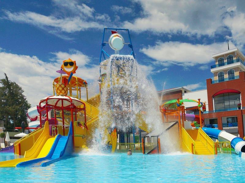 Barevné vodní hřiště se skluzavkami a bazénem pod modrou oblohou v rekreačním středisku.