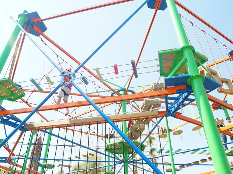 Barevná konstrukce lanového centra s různými lezeckými prvky a lany pod jasnou oblohou