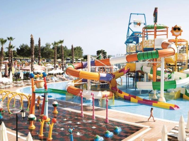 Barevný vodní park s tobogány a bazény pod jasnou oblohou.