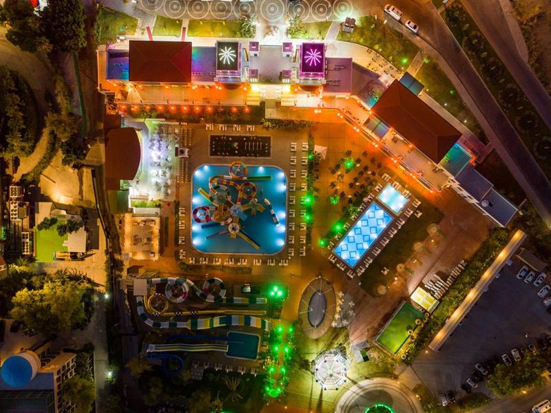 Letecký pohled na osvětlený hotel s bazénem a zahradou v noci