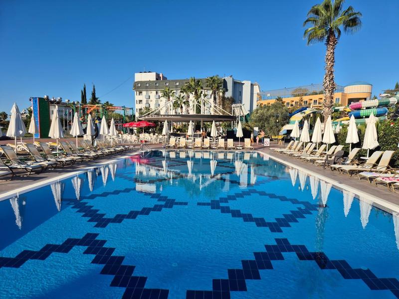 Velký hotelový bazén s lehátky a slunečníky pod jasnou oblohou