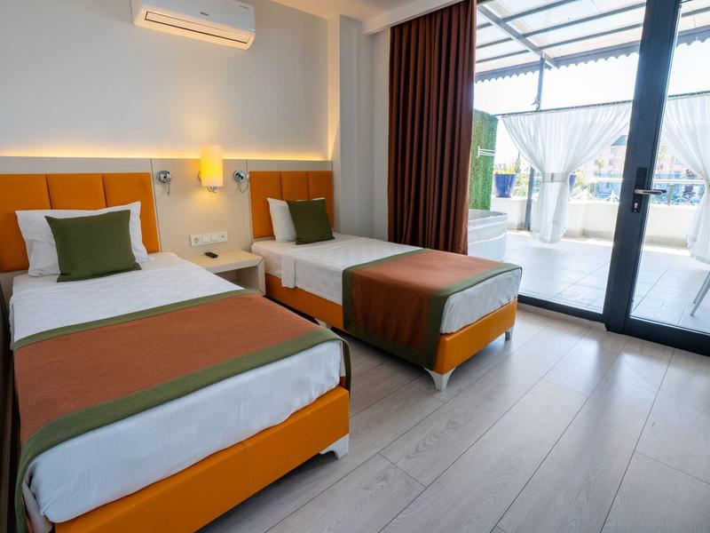 Hotelový pokoj se dvěma oddělenými postelemi, moderní dřevěnou podlahou a přístupem na terasu.