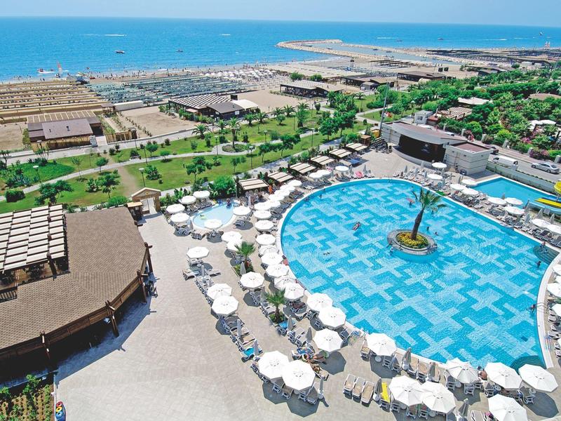 Grande piscina dell'hotel con ombrelloni e vista sul mare e la costa.