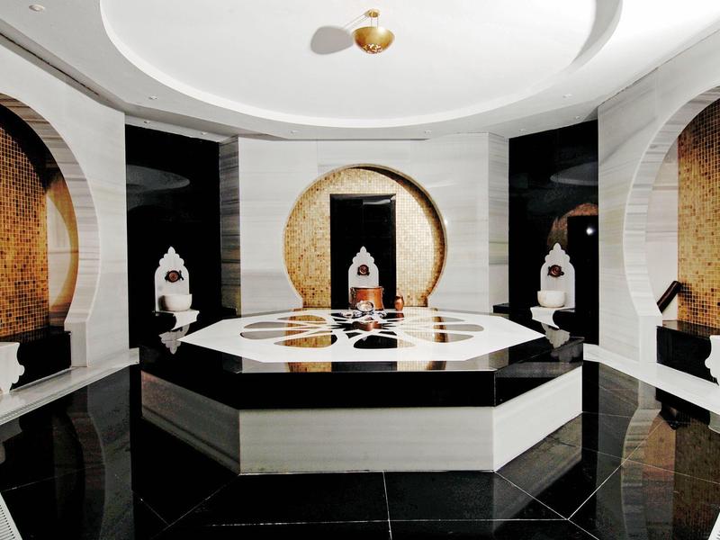 Bagno turco moderno con vasca centrale in marmo e dettagli artistici.