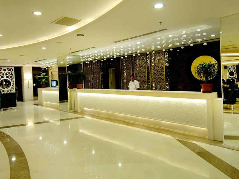 Area di accoglienza in hotel moderna ed elegante con banco illuminato e pavimento lucido.