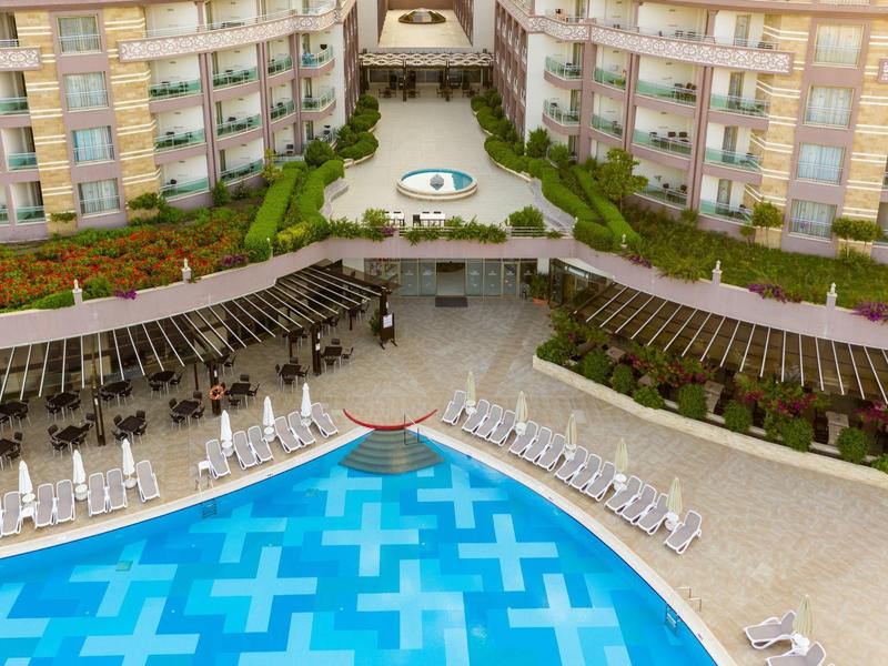 Vista di una piscina dell'hotel con lettini e edifici adiacenti.