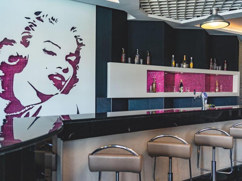 Bar d'hotel moderna con grande murale di Marilyn Monroe e sgabelli eleganti