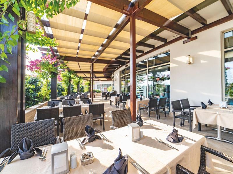 Accogliente terrazza esterna di un ristorante con tavoli apparecchiati sotto una tenda.