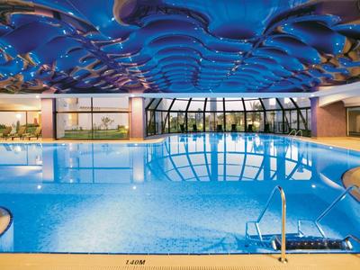Moderner Innenpool mit blauem Wellenmuster an der Decke und großen Fensterfronten.