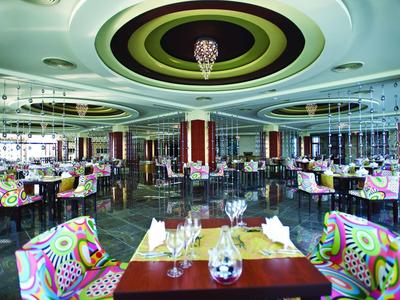 Buntes modernes Restaurant mit runden Deckenlampen und vielen Tischen, dekoriert mit Gläsern und Servietten.