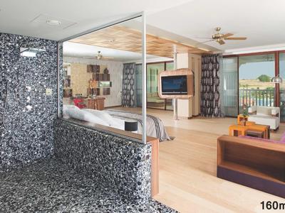 Großes Wohnzimmer mit Sofa, Fernseher, Holzboden und Balkon mit Meerblick, daneben Marmorbad mit großer Dusche.