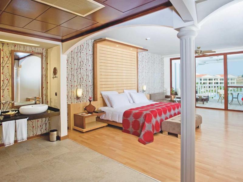 Modern hotel room with open bathroom and balcony overlooking other buildings.