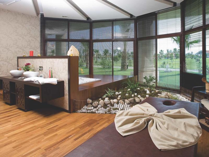Modern spa with wooden flooring, bean bags, and large windows overlooking greenery.