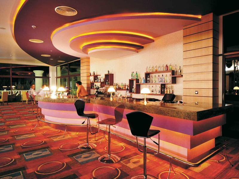 Elegant hotel bar area with curved counter, stylish bar stools, and warm lighting.
