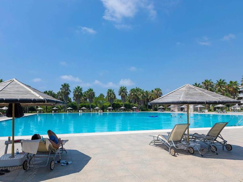Large hotel pool with lounge chairs and umbrellas on a sunny day.