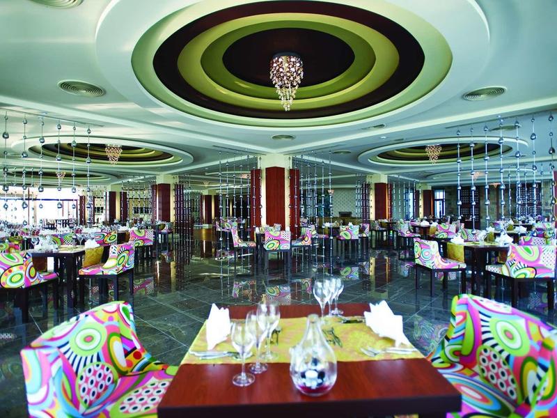 Modern restaurant with colorful chairs and elegant decor in a bright setting.