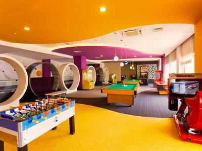 Bunter Spielraum mit Kicker, Billardtisch, runden Sitznischen und Arcade-Spielautomaten.