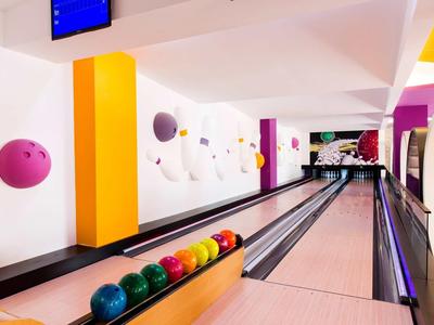 Moderne Bowlingbahn mit bunten Kugeln und hellen Wänden in Weiß, Gelb und Violett.