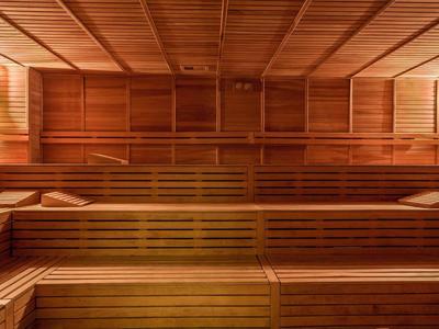 Holzsauna mit mehrstufigen Sitzbänken und gedämpftem, warmem Licht an den Wänden.