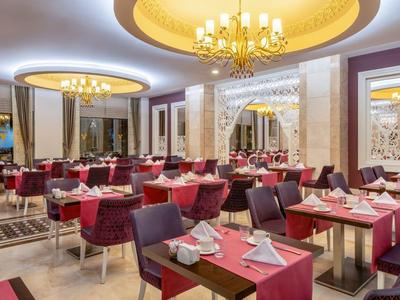 Ristorante elegante con tavoli apparecchiati, lampadari e illuminazione calda.