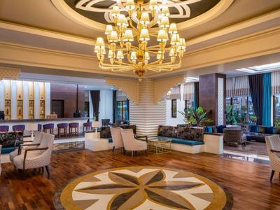 Lounge elegante dell'hotel con lampadari, poltrone confortevoli e grandi finestre.