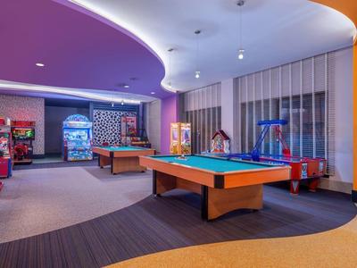Area sala giochi ben illuminata con tavolo da biliardo e varie macchine arcade.