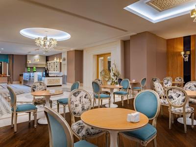 Sala da pranzo elegante dell'hotel con tavoli rotondi, sedie blu e lampadari.