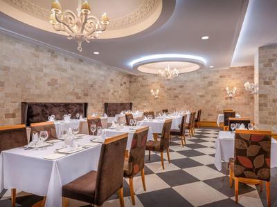 Sala da pranzo elegante con tovaglie bianche, lampadari raffinati e sedie con motivo.