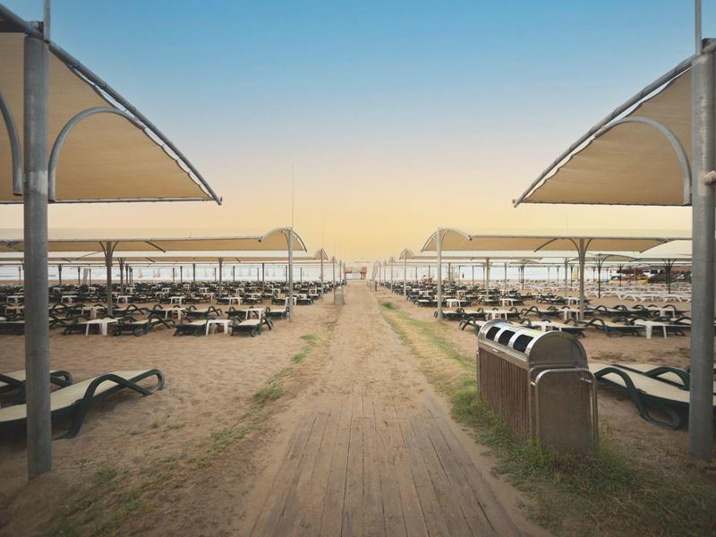 Spiaggia vuota con ombrelloni e lettini all'alba.