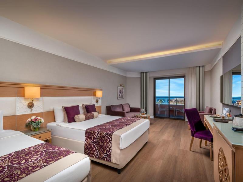 Camera d'hotel moderna con letto matrimoniale, zona salotto e balcone con vista.