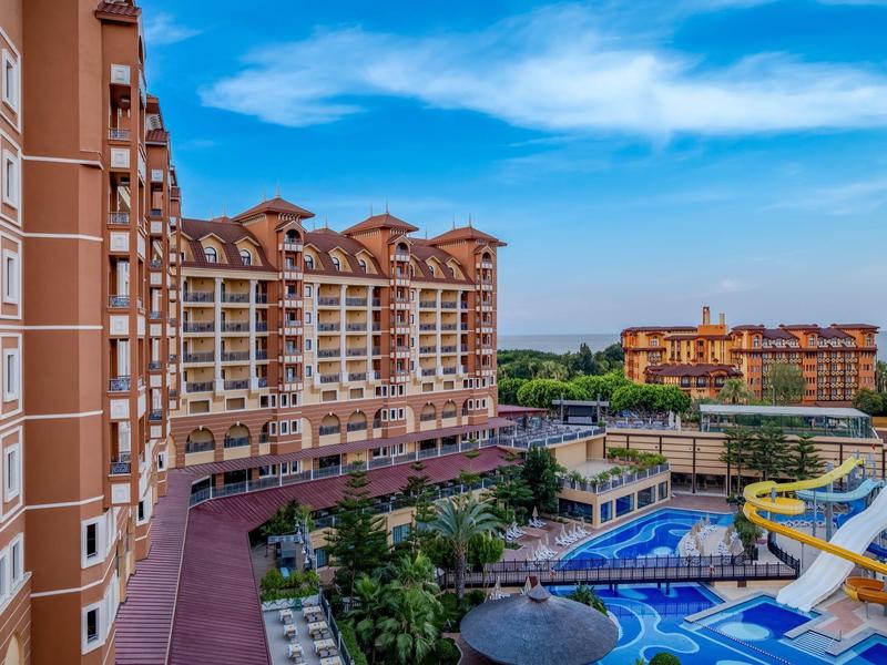 Vista di un hotel con piscina e scivoli d'acqua sotto un cielo azzurro.