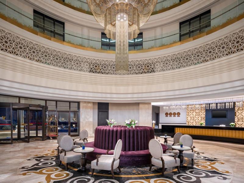 Ampia hall dell'hotel con area salotto rotonda e grande lampadario.