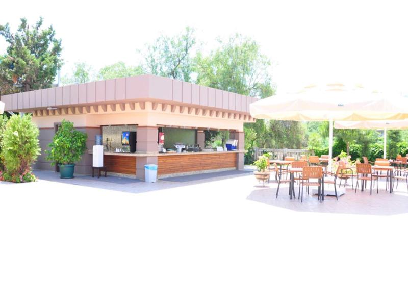 Bar all'aperto con posti a sedere e grande ombrellone in un'area esterna soleggiata.