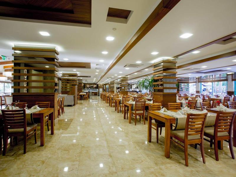 Grande ristorante ben illuminato con molti tavoli e sedie in legno.