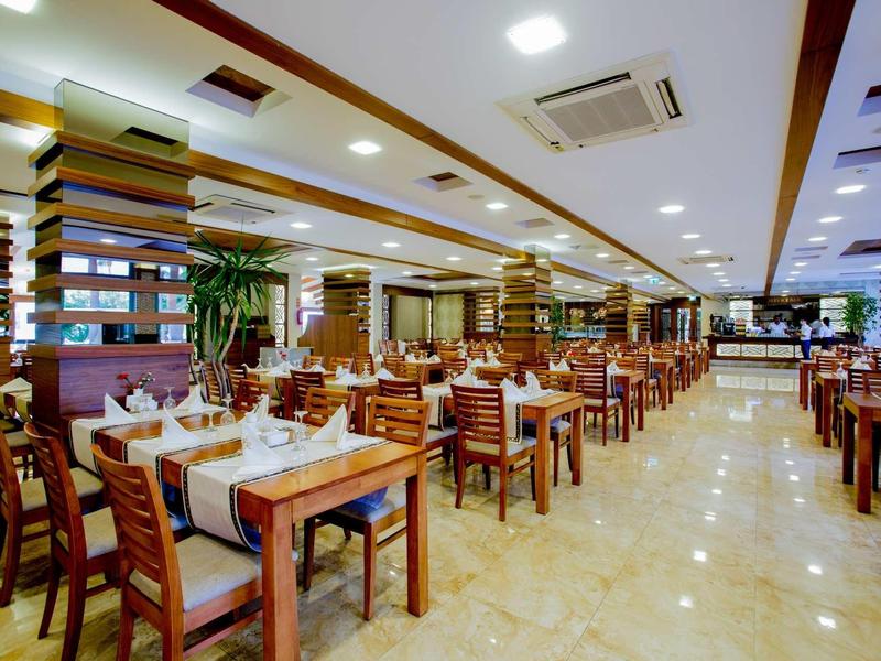 Ampia sala ristorante con sedie in legno, tavoli apparecchiati e pavimento in marmo chiaro.