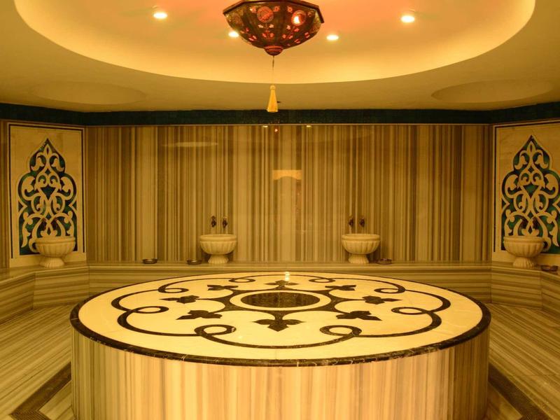 Piattaforma rotonda decorativa in pietra in un hammam dallo stile tradizionale con illuminazione calda.