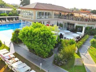 Große Wohnung mit braunem Dach und Terrasse, umgeben von grünem Garten und blauem Pool.
