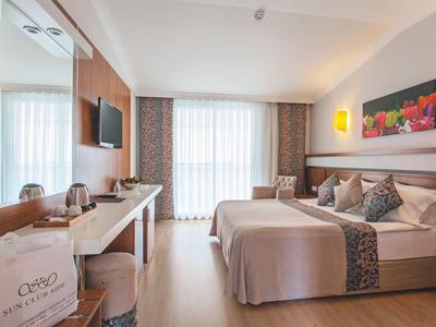 Camera d'albergo moderna con letto matrimoniale, scrivania e grande finestra con tende.