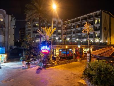 Verlicht hotel en restaurant 's nachts met palmbomen en straatdecoraties.