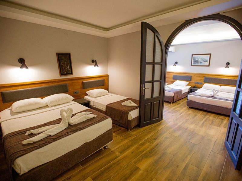 Twee aangrenzende hotelkamers met houten vloeren en elk twee bedden, gescheiden door een glazen deur.