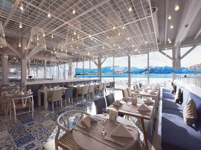 Hell gestaltetes Restaurant mit Holzmöbeln, blauen Kissen und großem Panoramafenster mit See- und Bergblick.