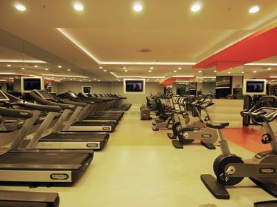Ein heller Fitnessraum mit Laufbändern und modernen Cardiogeräten, organisiert in Reihen.